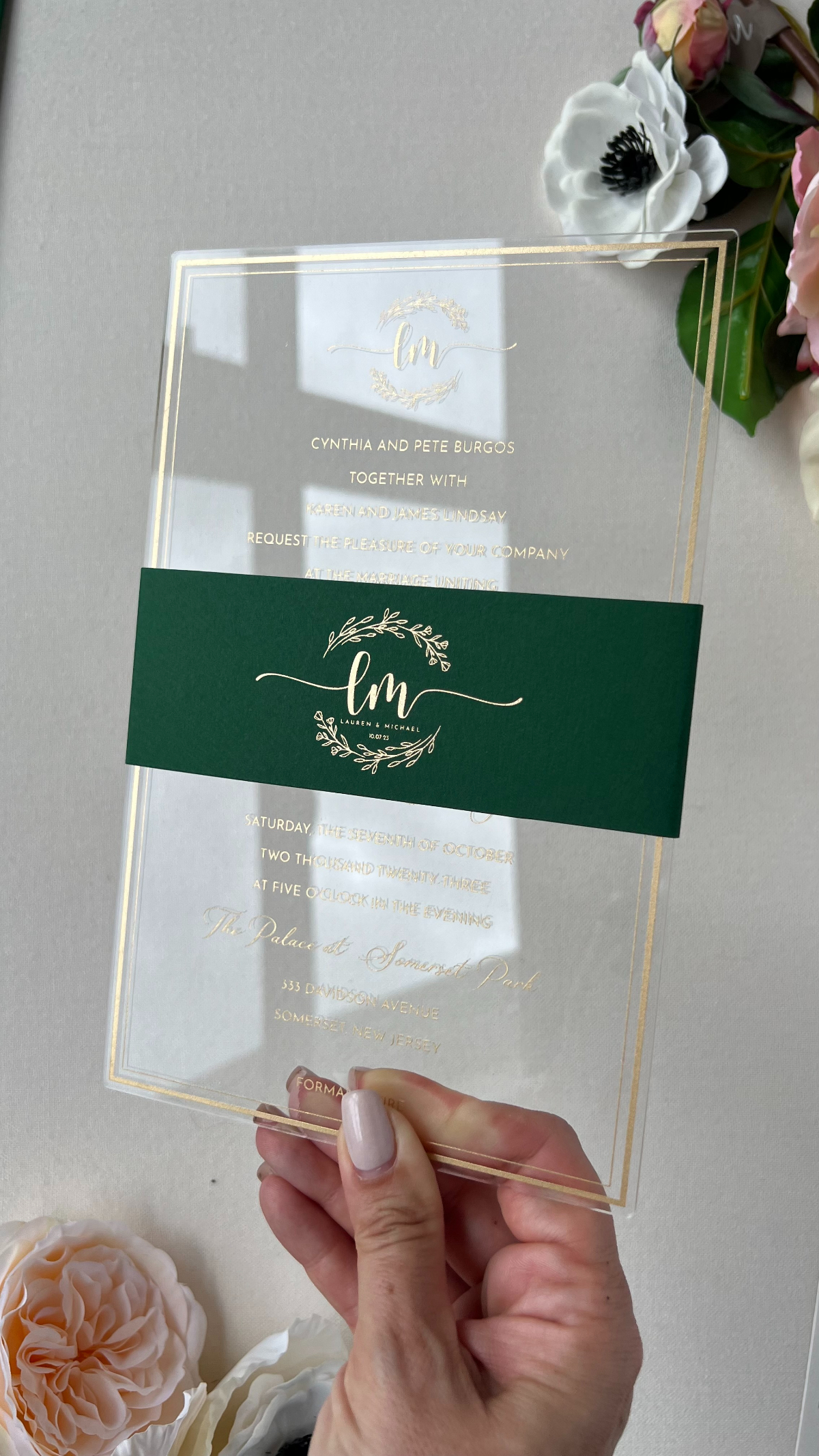 Modern acrylic invitation with gold foil typography and a deep green belly band, a sleek custom wedding invitation design blending transparency, minimalism, and luxury details.