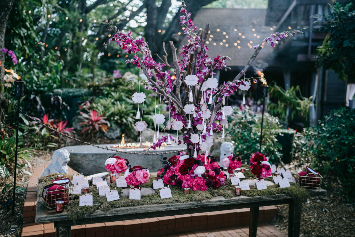 Vibrant escort card display with bold florals and decorative elements set in a lush garden, adding personality and color to a destination wedding in Florida.
