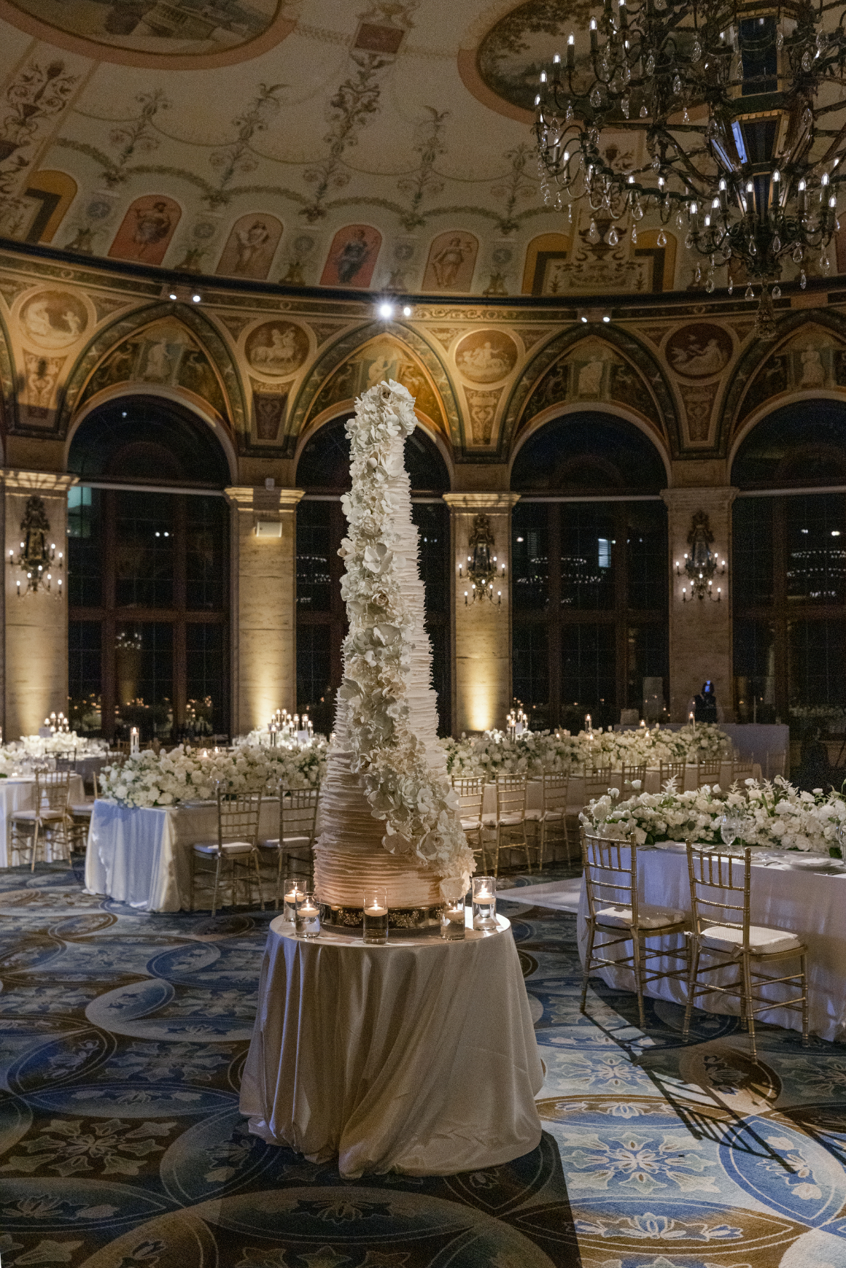 Elegant wedding reception ballroom with a dramatic multi-tiered cake, candlelight, and floral arrangements, creating a luxurious atmosphere for a destination wedding in Florida celebration.