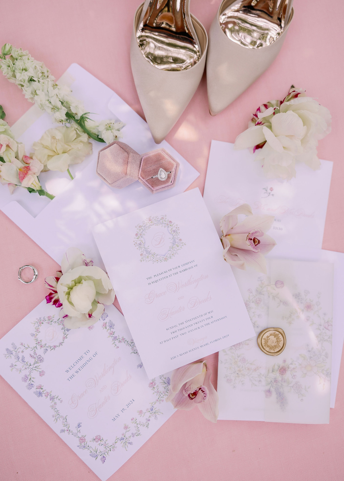 Soft blush and pastel floral wedding invitation suite with vellum overlays, ring box, and bridal shoes, styled on a pink backdrop, capturing a romantic and airy feel perfect for a destination wedding in Florida.